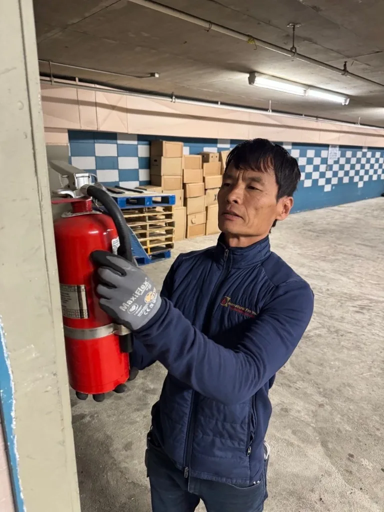 A technician from Fire Safety Industries installing and testing a portable fire extinguisher in a commercial building in Albuquerque